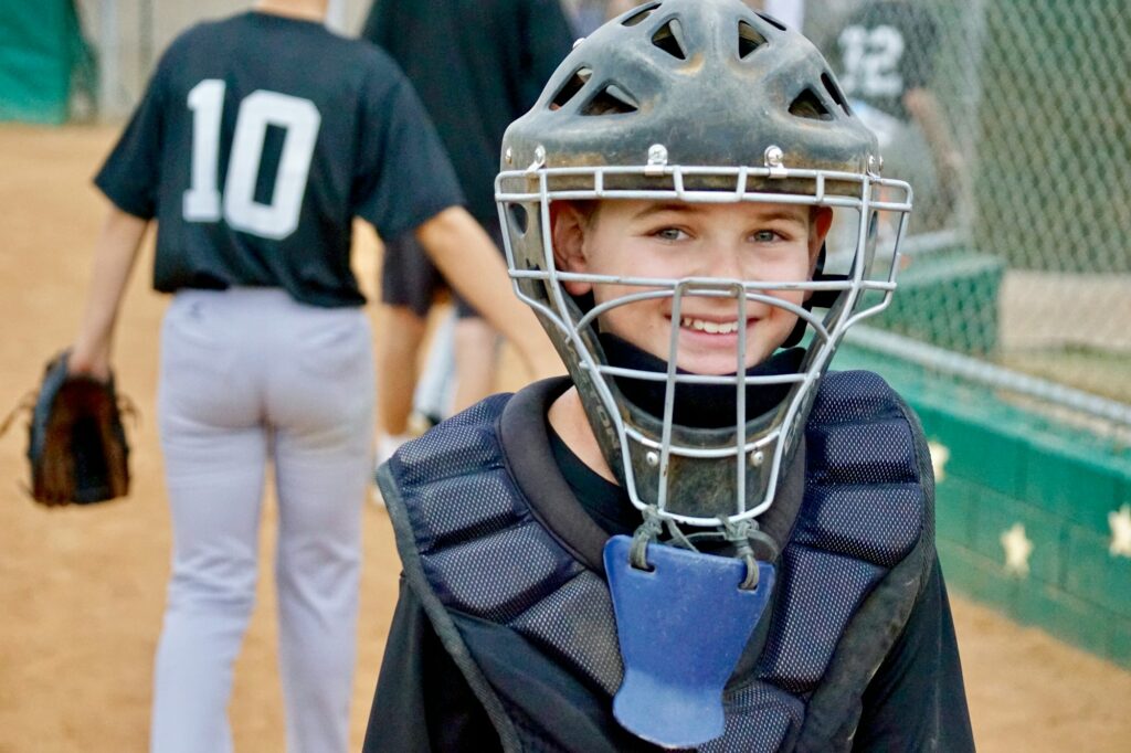 An amazing, happy and awesome kid, smiling after a baseball game, well played